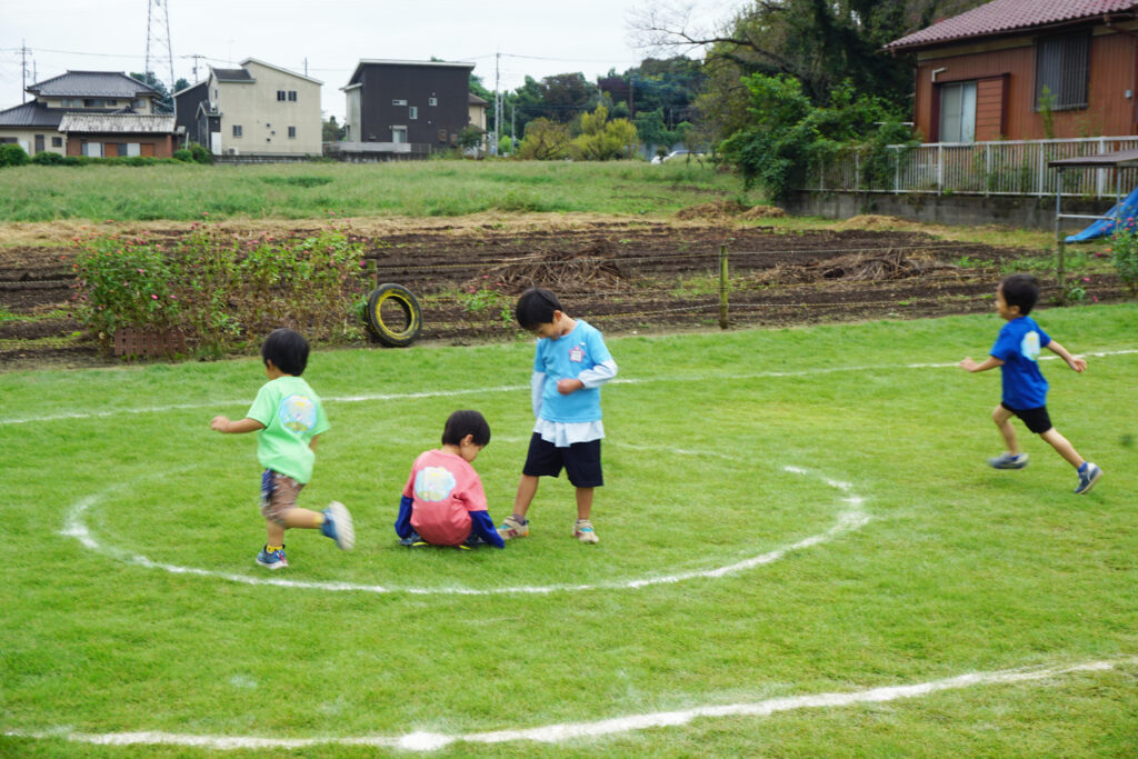 芝生の園庭で遊びまわる子どもたち